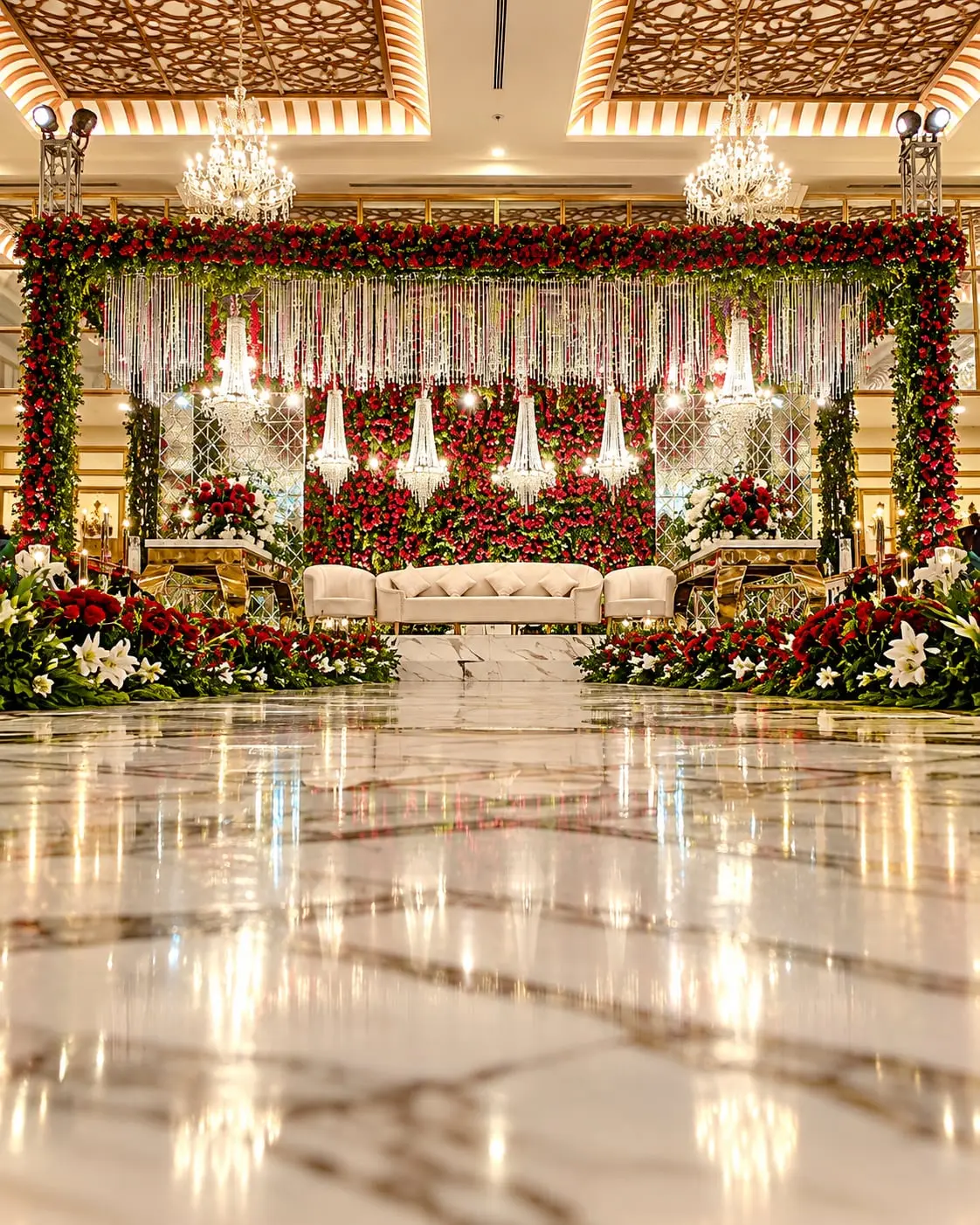 A stage banked with red and white roses under crystal drops