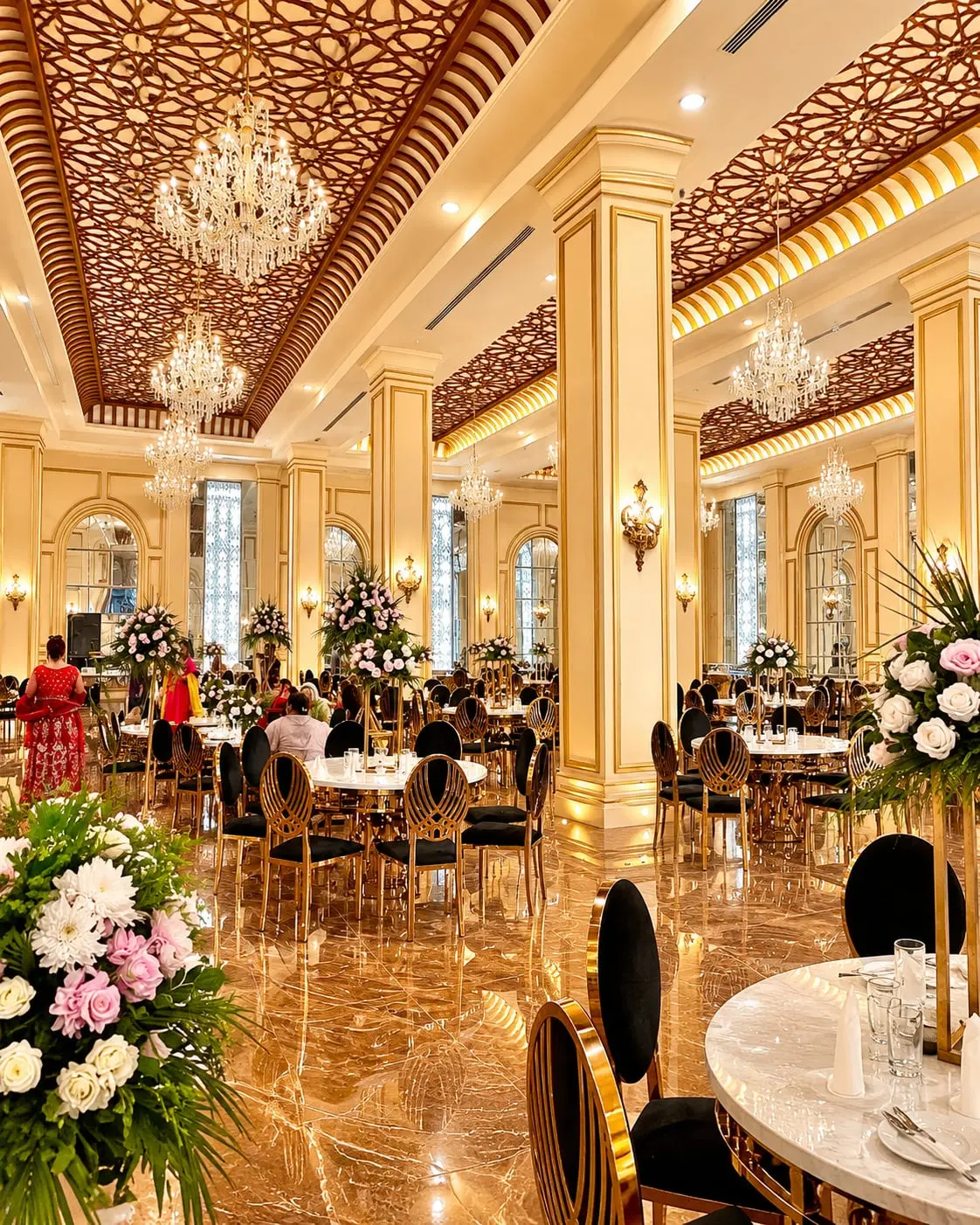 The length of the hall, its columns and chandeliers above tables set for guests