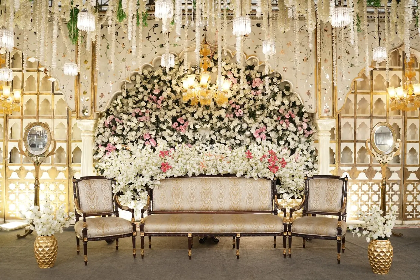 A bridal stage set beneath a floral arch