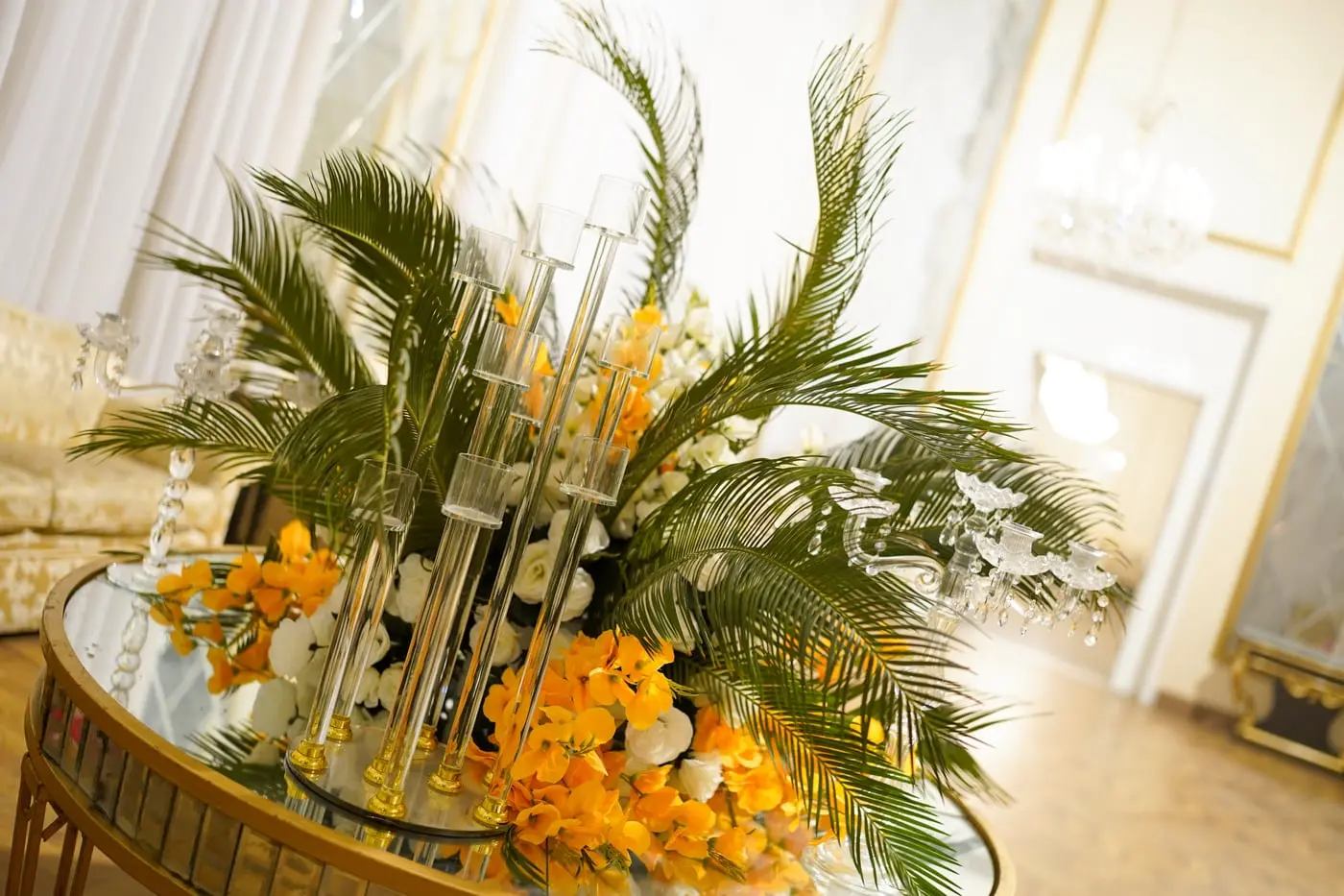An orchid and palm centrepiece on a mirrored table