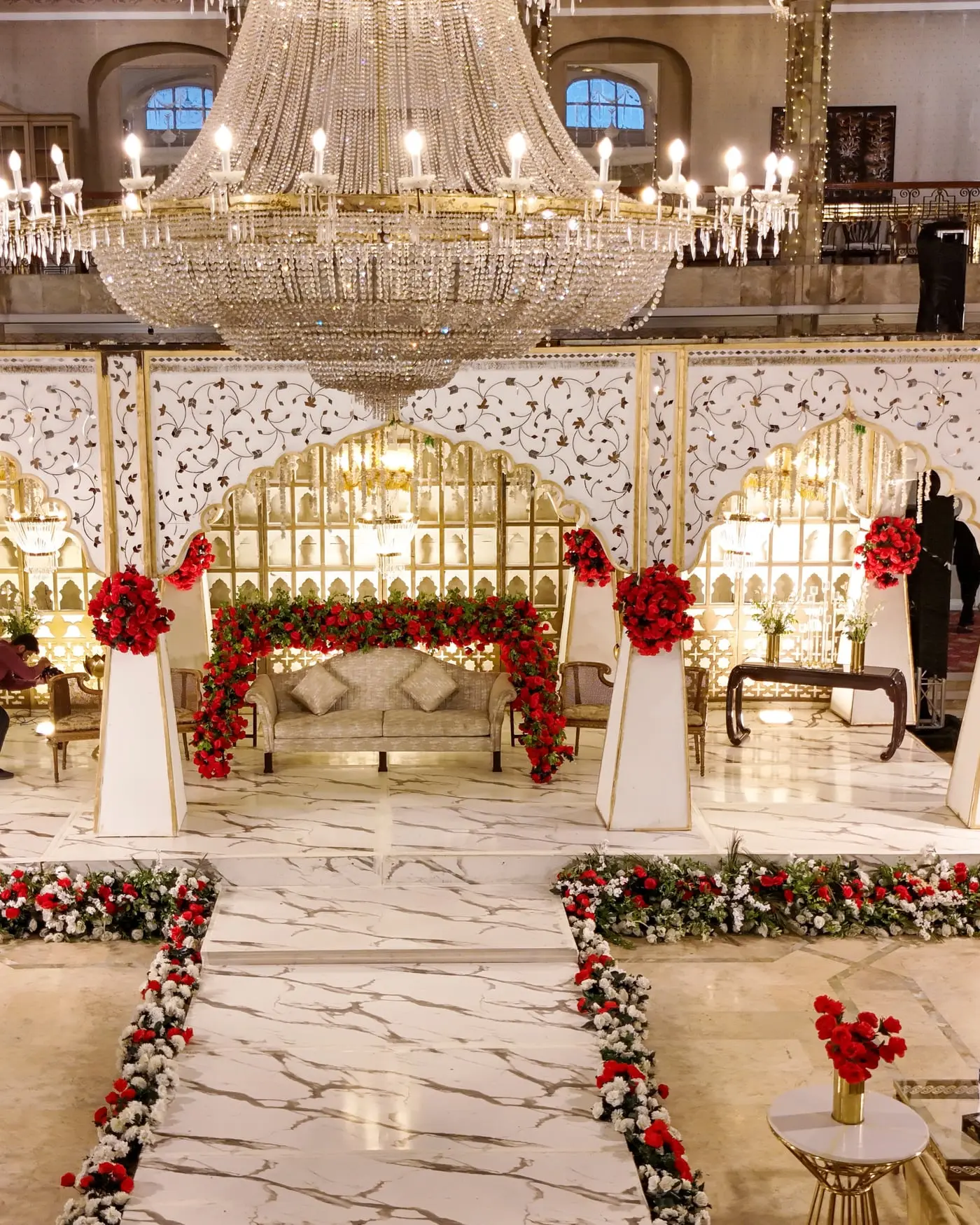 A wedding stage and garlanded aisle set in a hall at The Palace Banquet
